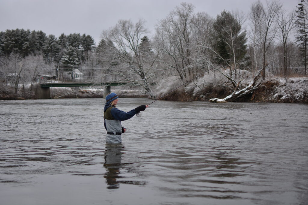 An angler fishing a river in winter